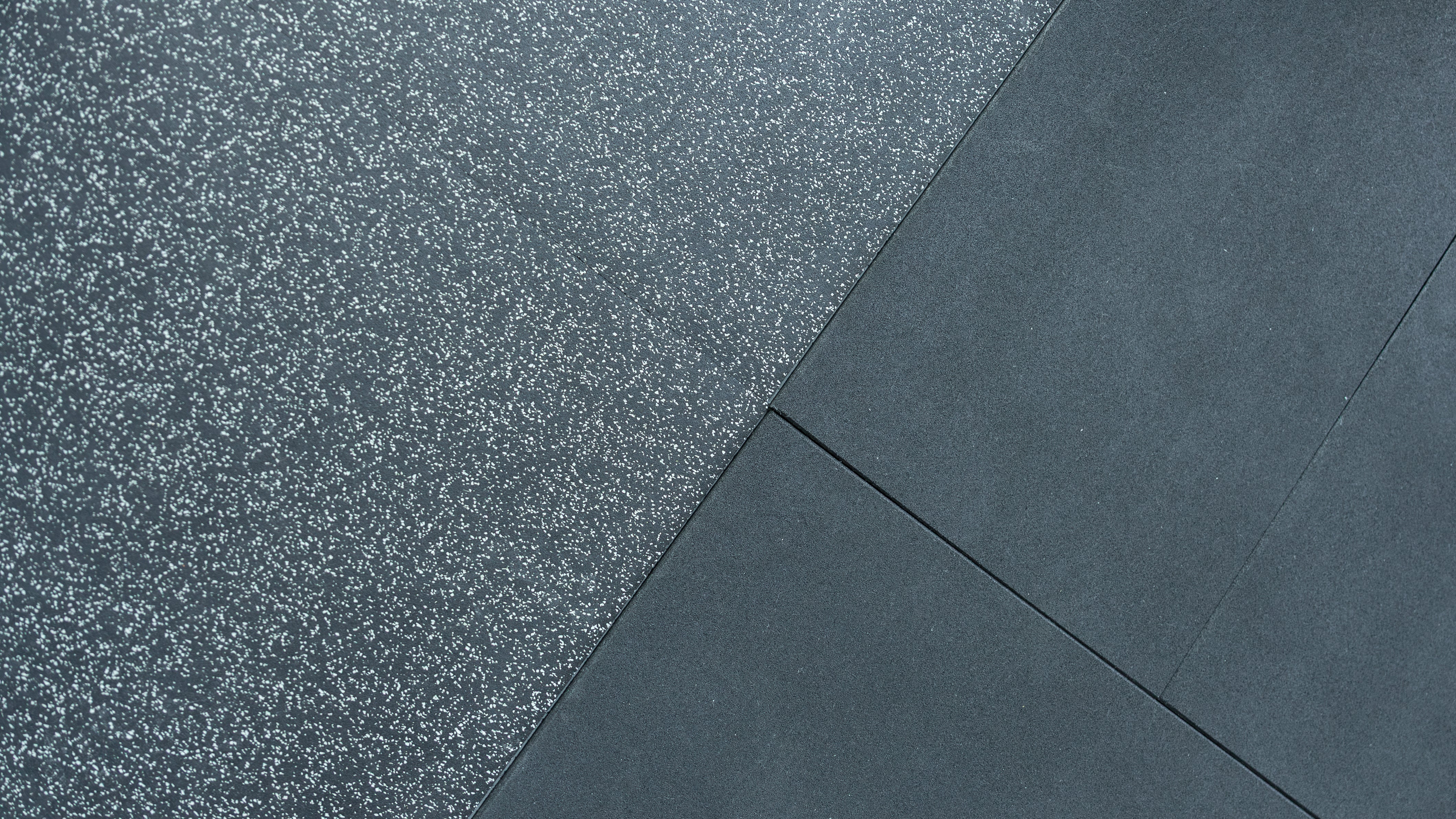 Close-up of textured black gym floor with a diagonal line