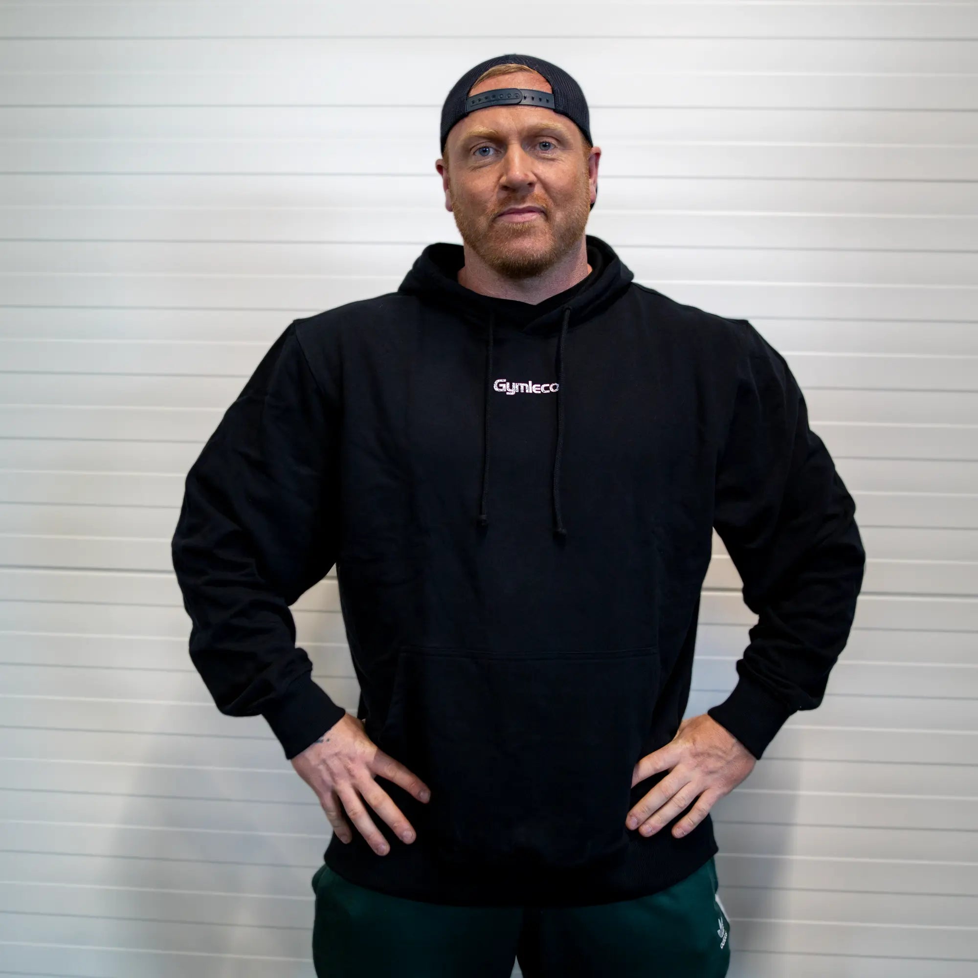 Man wearing a black hoodie with 'Gymleco' logo against a white background