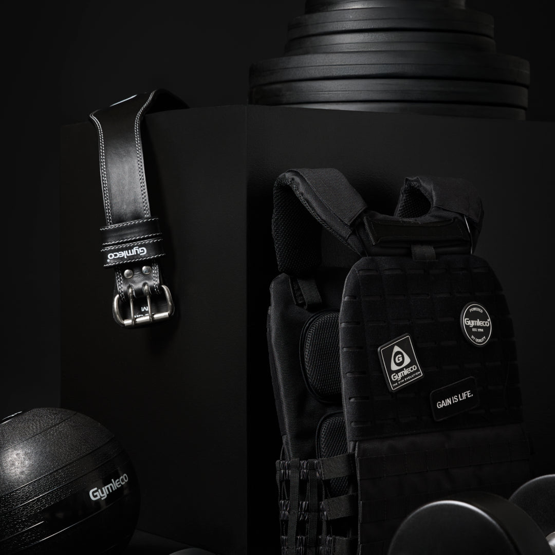 Black gym equipment including weights and a belt on a dark background