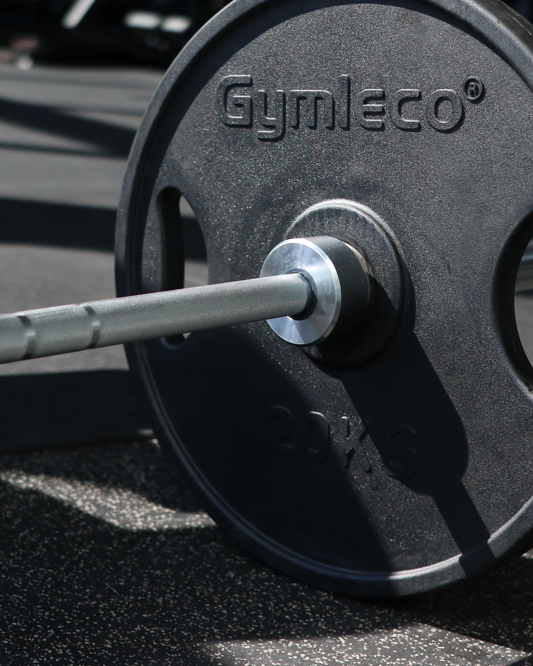 Barbell with Gymleco weight plates on a gym floor