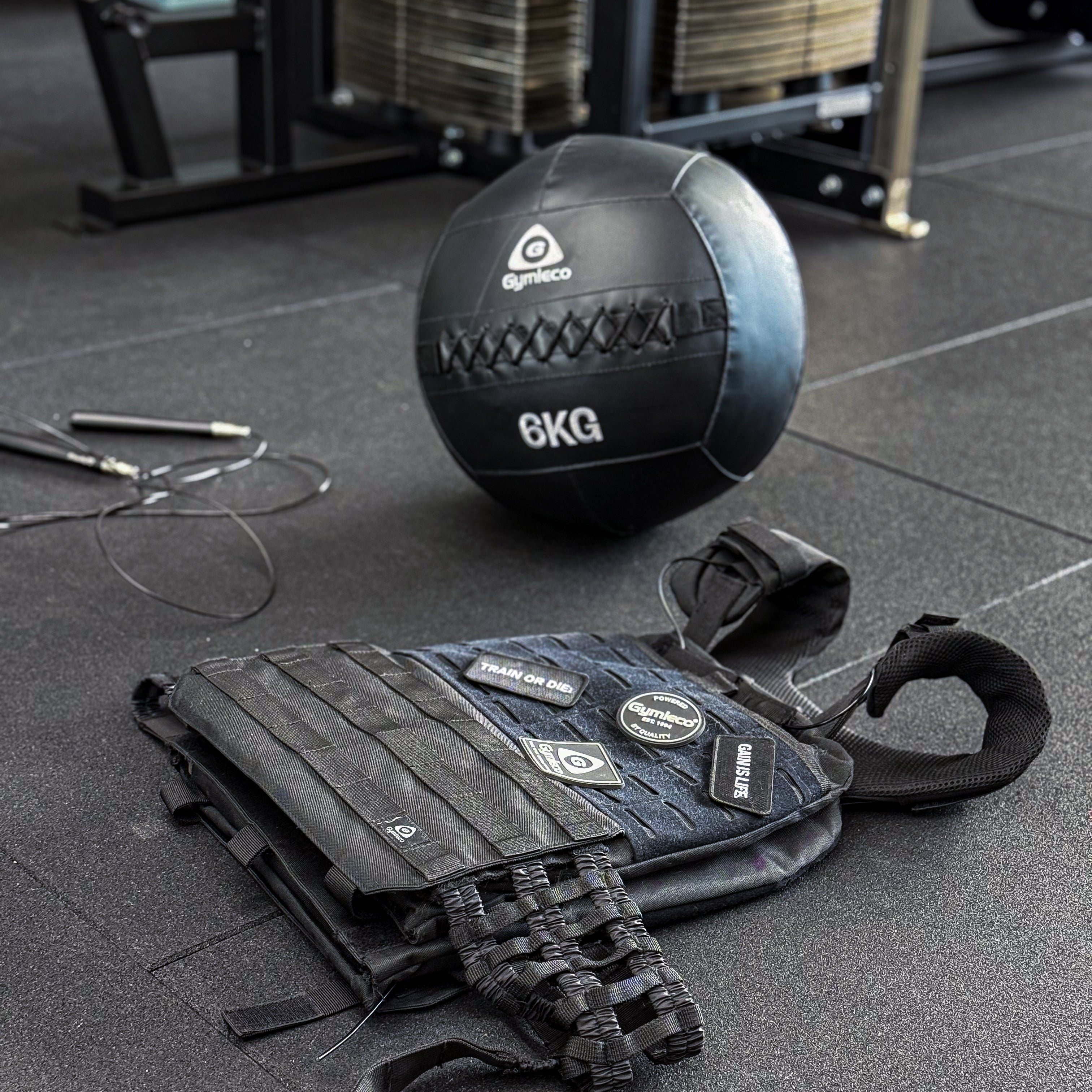 A weight west with patches, laying on the ground. A medicine ball and jumping ropes in the back.