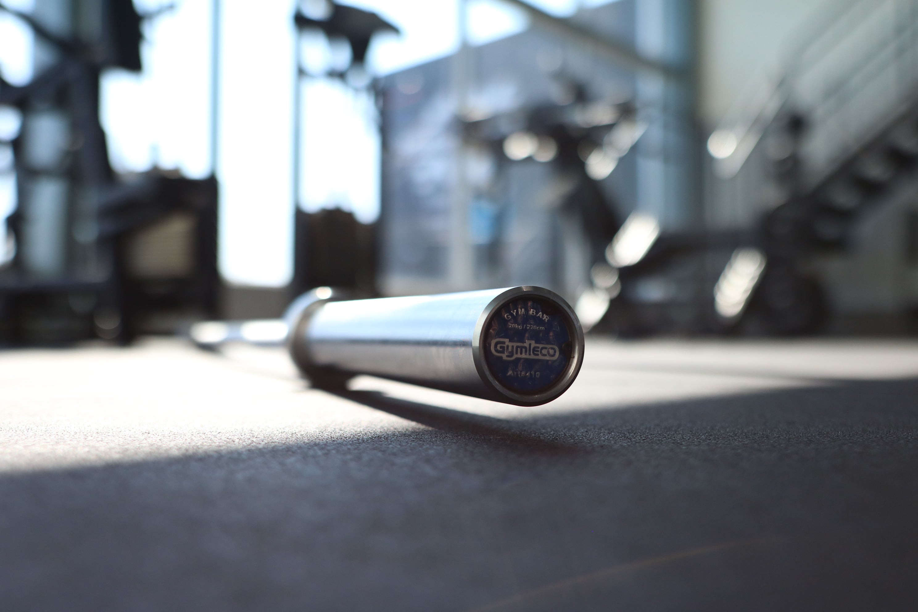 Barbell on a gym floor with blurred gym equipment in the background