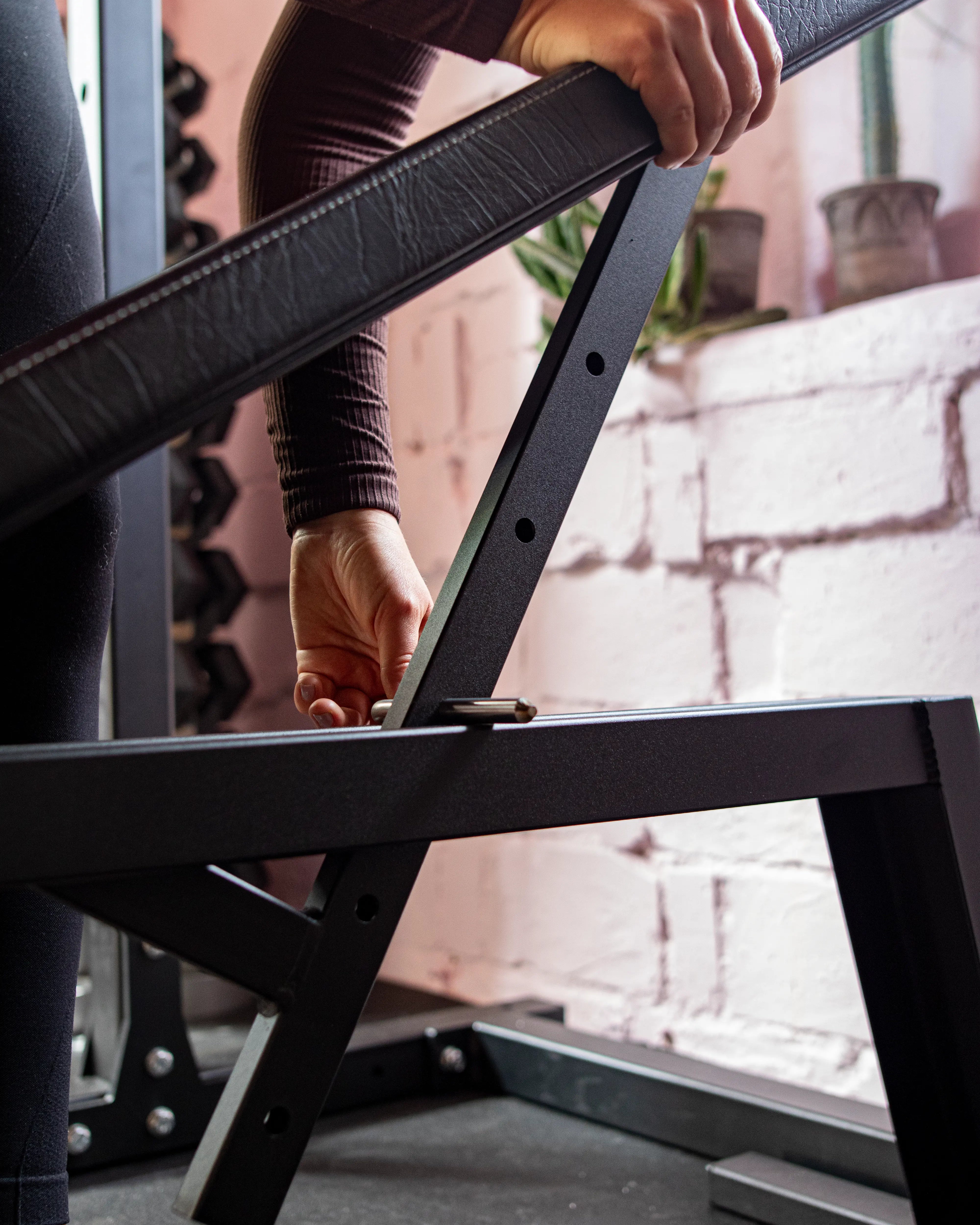 Person assembling a black metal frame on a bench with a blurred background