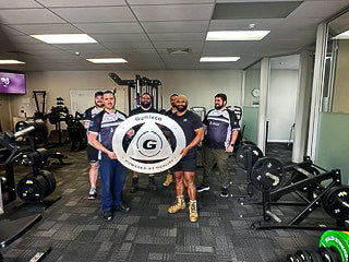 People holding a big "Gymleco" logo in a gym.