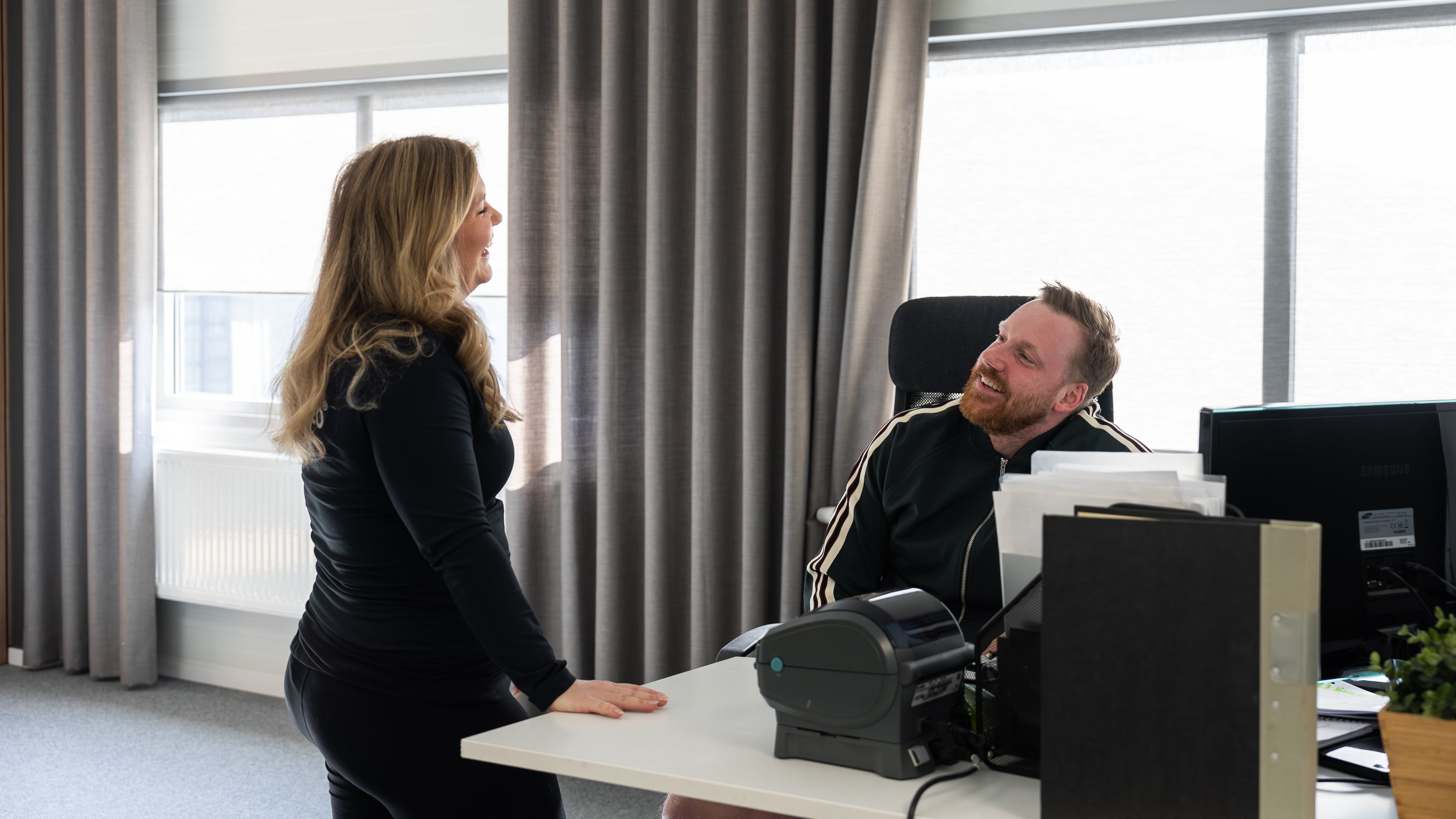 Two people at the Gymleco office, laughing.