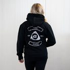 Person wearing a black hoodie with a logo and text on the back against a white background