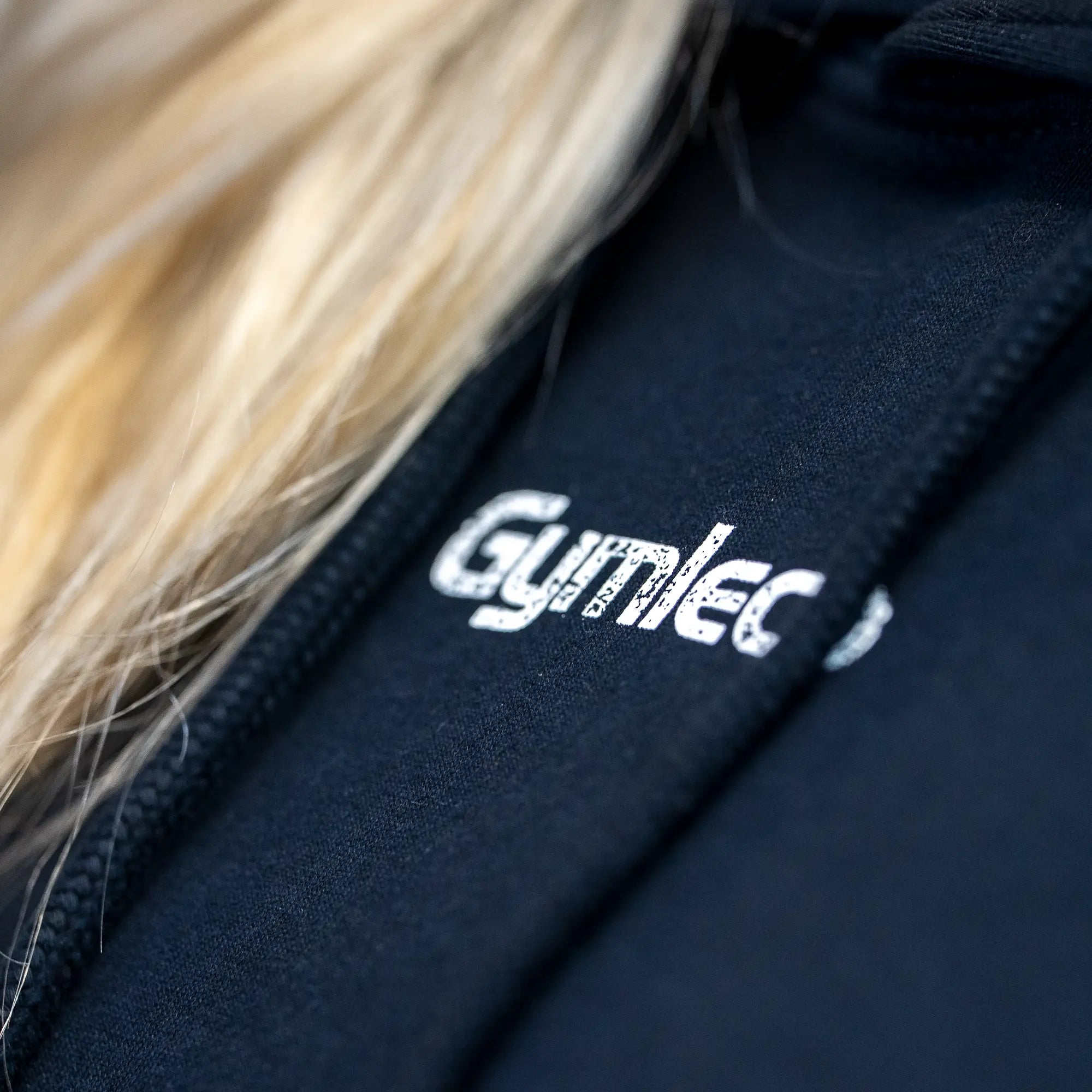 Black fabric hoodie with 'Gymlec' logo, close-up view.