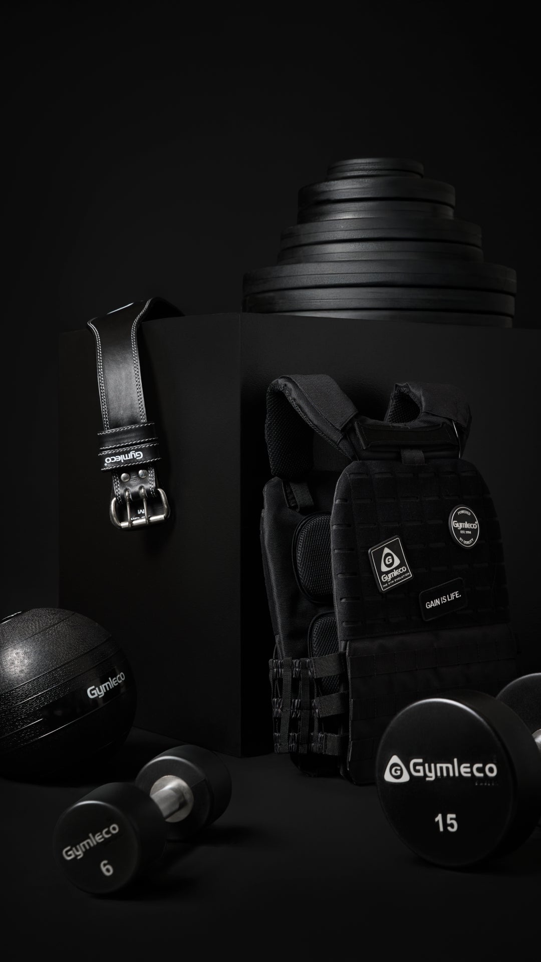 Black gym equipment including weights and a belt on a dark background