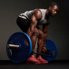 Athlete lifting a barbell with blue weights on a dark background