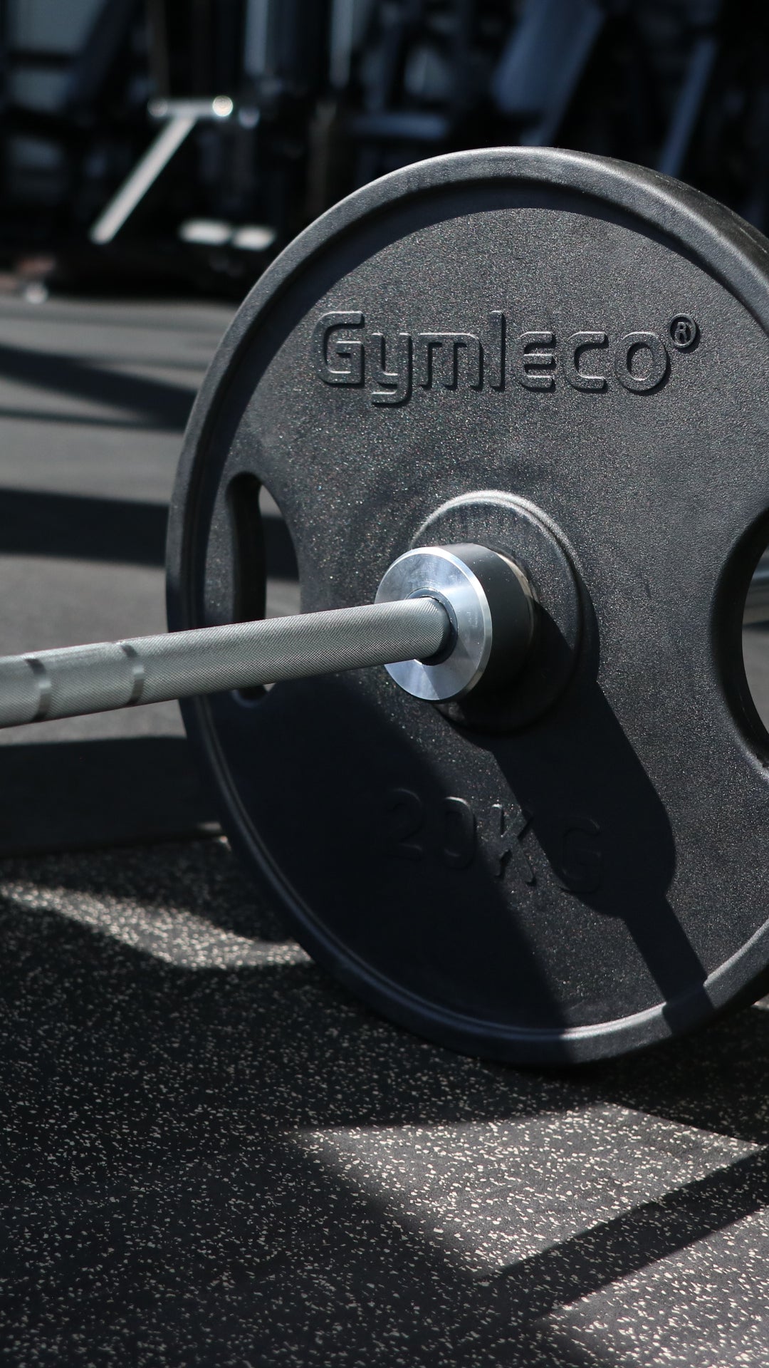 Barbell with Gymleco weight plates on a gym floor