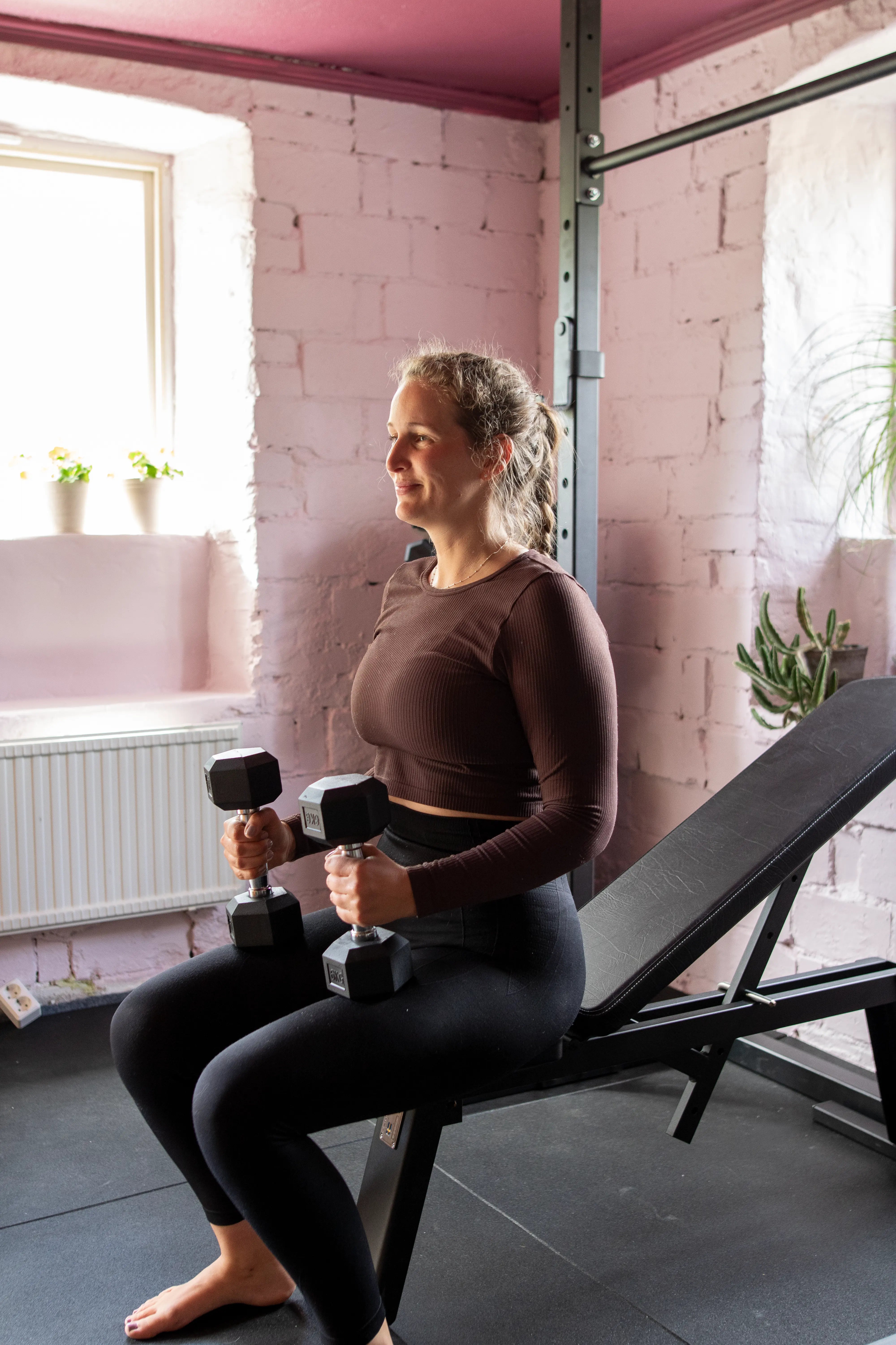 Woman exercising with dumbbells in a home gym setting.